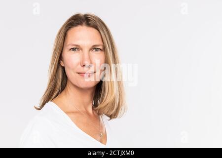 Primo piano di donna matura sorridente con capelli biondi contro bianco sfondo Foto Stock