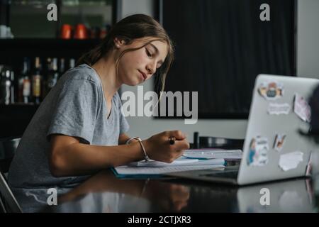 Ragazza adolescente che studia da casa, utilizzando un computer portatile Foto Stock