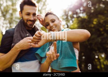 Uomo e donna sportivi che guardano uno smartwatch in uno parcheggio Foto Stock