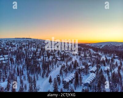 Finlandia, Lapponia, Saariselka, veduta aerea del villaggio montano innevato al tramonto Foto Stock