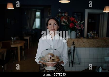 Donna che tiene i biscotti in piastra con chioche al caffè negozio Foto Stock