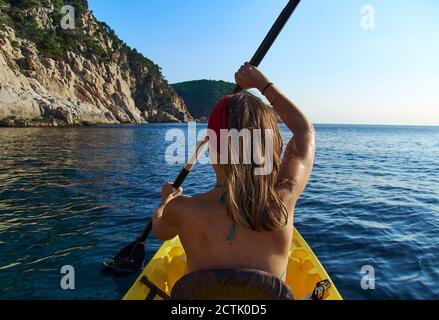 Donna in kayak mentre si siede in barca contro il cielo limpido Foto Stock