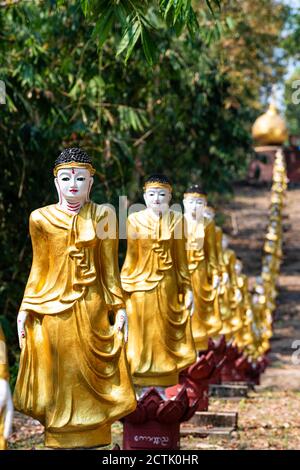 Fila di statue dorate di Buddha in piedi all'aperto Foto Stock
