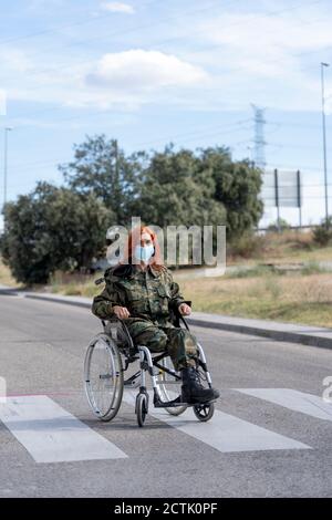 Soldato dell'esercito seduto su sedia a rotelle mentre indossa una maschera protettiva Foto Stock