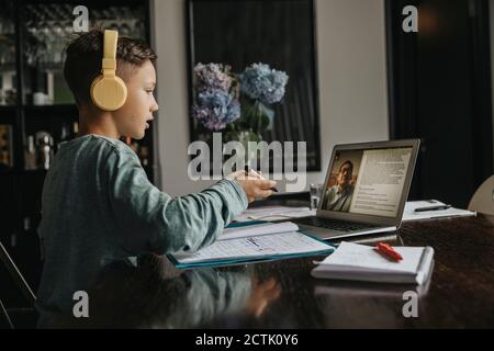 Studente che impara a casa, utilizzando il laptop e le cuffie Foto Stock