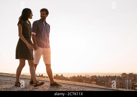 Coppia che tiene le mani mentre si cammina sulla strada durante il tramonto Foto Stock