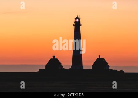 Germania, Schleswig-Holstein, Westerhever, Silhouette di Westerheversand Faro a Moody alba Foto Stock