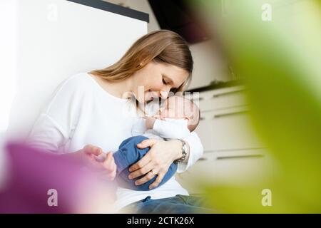 Madre che tiene il bambino addormentato nelle braccia a casa Foto Stock