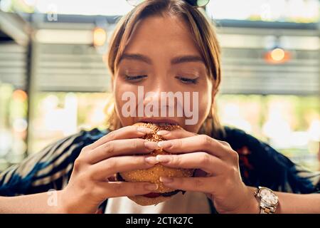 Ritratto di donna che mangia un hamburger Foto Stock