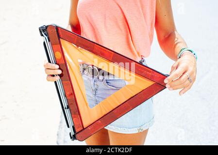 Primo piano di una donna che tiene un triangolo di avvertimento Foto Stock