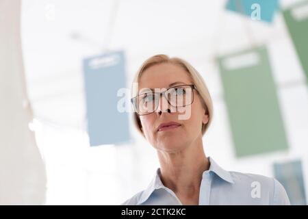 Primo piano di donna d'affari pensieroso che indossa occhiali che guardano via in casa ufficio Foto Stock
