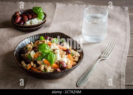 Ciotola di spaetzle vegetariano con carote, olive, formaggio feta e basilico Foto Stock