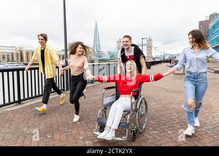 Uomini e donne allegri con amica disabile che si godono in città, Londra, Regno Unito Foto Stock