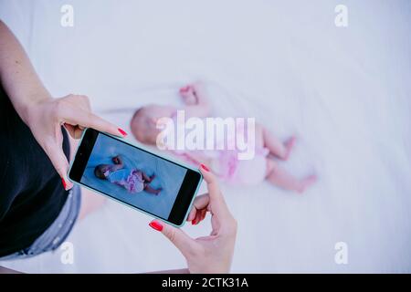 Donna che scatta la foto della bambina che dorme sulla coperta Foto Stock