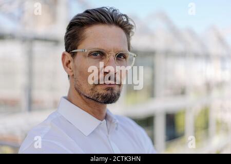 Primo piano di un serio uomo professionista che indossa occhiali in vivaio di piante Foto Stock