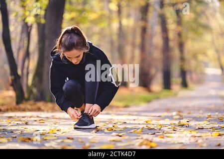 Giovane donna legando la sua scarpa da corsa Foto Stock