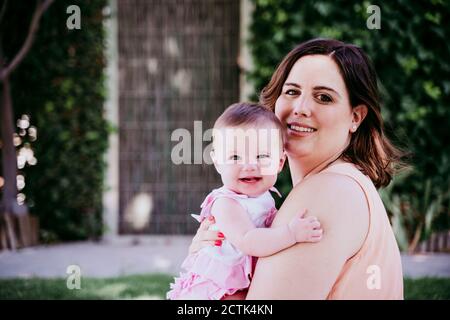 Madre felice che porta la bambina al cortile posteriore Foto Stock