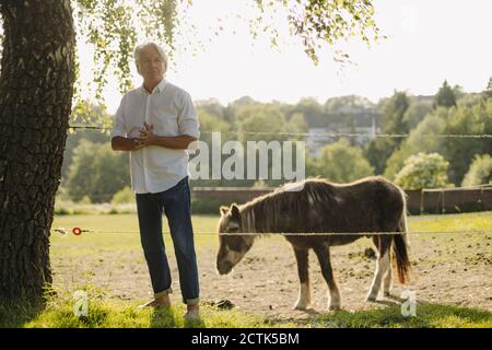 Uomo con le mani aggrappate in piedi da capra in campo Foto Stock