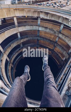 Regno Unito, Scozia, Edimburgo, gambe di uomo seduto al bordo del vialetto di parcheggio a spirale Foto Stock