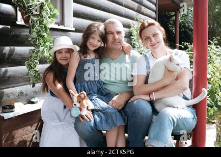 Famiglia seduta con gatto mentre si passa il tempo in veranda Foto Stock