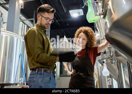 Uomo e donna che lavorano nel documento di controllo della fabbrica di birra artigianale Foto Stock