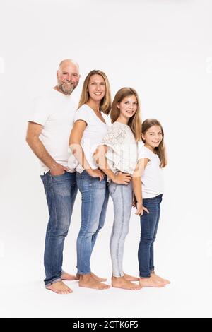 Famiglia sorridente con le mani sui fianchi in piedi su sfondo bianco Foto Stock