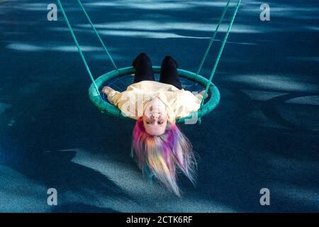 Giovane donna con i capelli tinti che giacciono sull'oscillazione Foto Stock