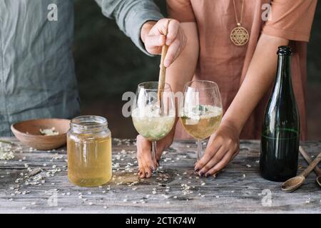 Metà dell'uomo mescolando il vino in bicchiere mentre si prepara il cocktail con la ragazza Foto Stock