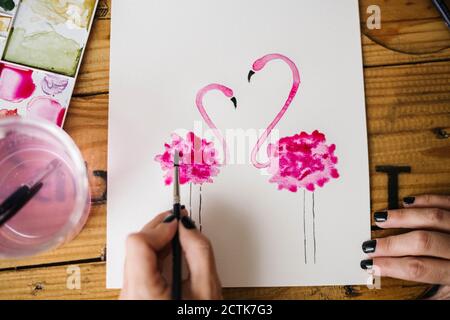 Primo piano di donna mano pittura animale fenicottero su carta Foto Stock