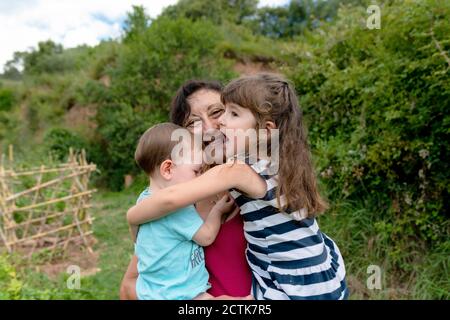 Nonna felice che abbraccia le nipote nel campo Foto Stock