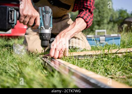 Carpentiere che tiene il trapano sulla tavola Foto Stock