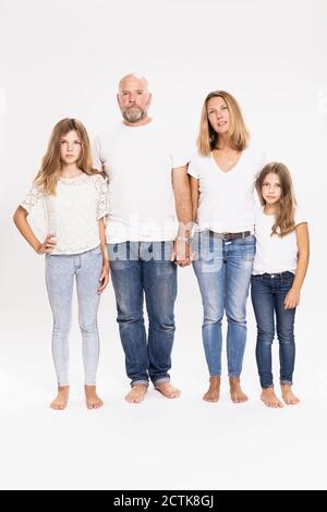 Famiglia che indossa t-shirt e jeans in piedi su sfondo bianco Foto Stock