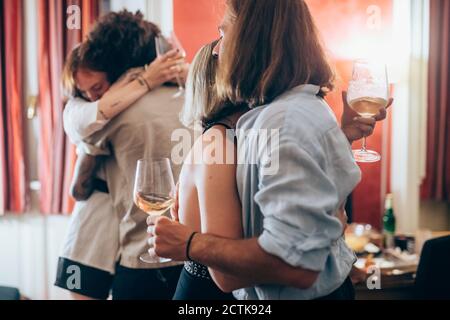 Amici di sesso maschile e femminile che si abbracciano durante la festa a casa Foto Stock
