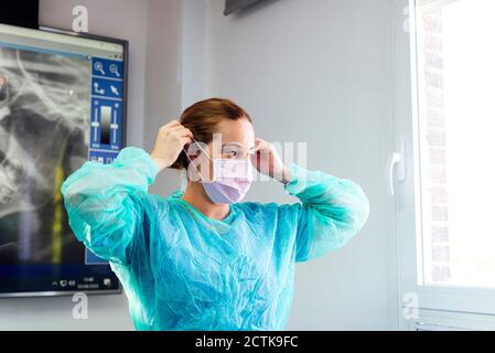 Dentista in tuta protettiva indossando maschera mentre si sta a. clinica Foto Stock