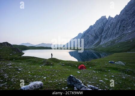 Cielo limpido sulla riva del lago Kogelsee all'alba con silhouette di camper solone in piedi sullo sfondo Foto Stock