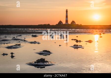 Germania, Schleswig-Holstein, Westerhever, Coastal puddle a Sinrise con Westerheversand Faro in background Foto Stock