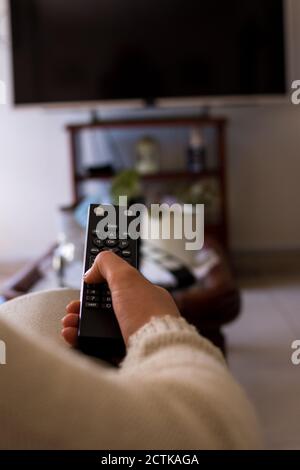 Ragazza seduta su un divano con telecomando tv nero controlista a casa Foto Stock