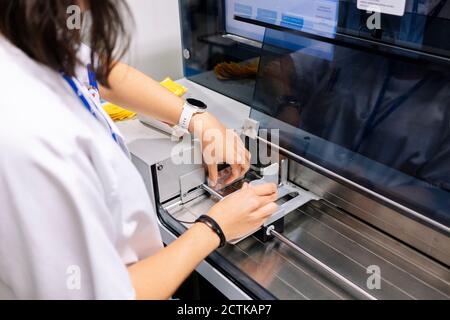 Primo piano di una farmacista femminile che utilizza un macchinario medico-organizzatore in ospedale Foto Stock