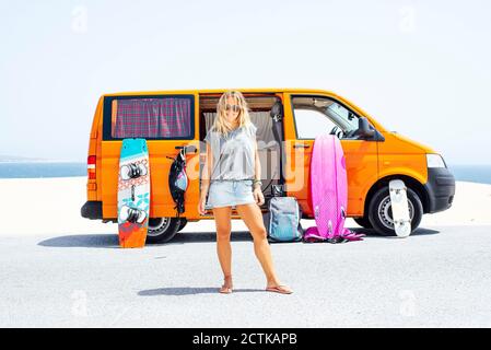 Donna bionda in piedi in spiaggia il giorno di sole Foto Stock