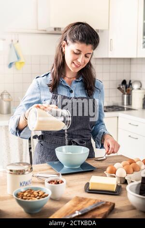 Bella donna che pesa la farina su scala da cucina per la torta da forno a casa Foto Stock