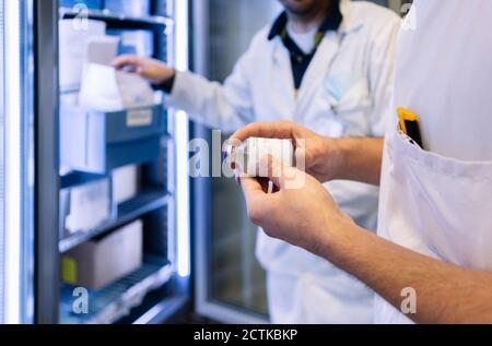 Primo piano di farmacisti maschili che prendono inventario in ospedale Foto Stock