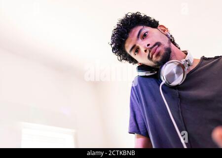 DJ giovane e sicuro che ascolta con le cuffie in studio di registrazione Foto Stock