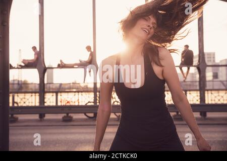 Donna che lancia i capelli in città al tramonto Foto Stock