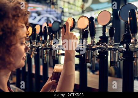 Barkeeper femminile che spillano la birra in un pub Foto Stock