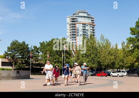 KELOWNA, BC, CANADA - 30 AGOSTO 2020: Un gruppo di turisti stranieri che prendono selfie di fronte ad una fontana nel centro di Kelowna. Foto Stock