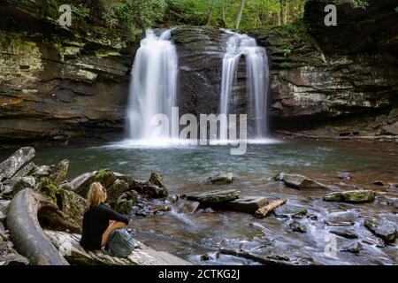 Una donna siede al Seneca Creek sotto le Cascate Seneca nella Spruce Knob/Seneca Rocks National Recreation Area, parte della Monongahela National Forest in W. Foto Stock