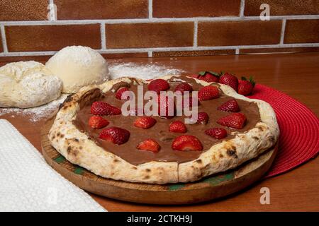 Pizza al cioccolato e fragole su tavola di legno Foto Stock