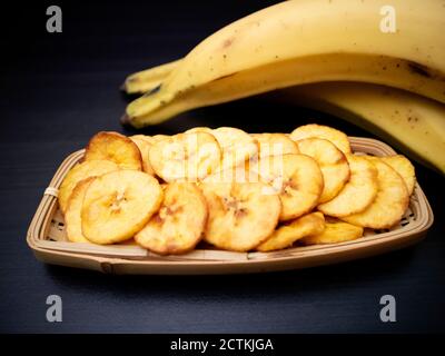 Chip di banana su sfondo scuro. Delizioso spuntino sano. Foto Stock