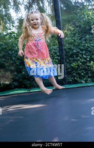 ragazza di 3 anni che si diverta saltando sul suo trampolino Foto Stock