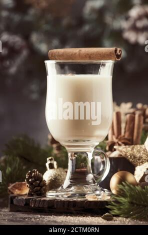 Cocktail alcolico Eggnog di Natale o Capodanno - bevanda calda invernale con latte, uova e rum, cosparsa di cannella e noce moscata in vetro su sfondo grigio Foto Stock